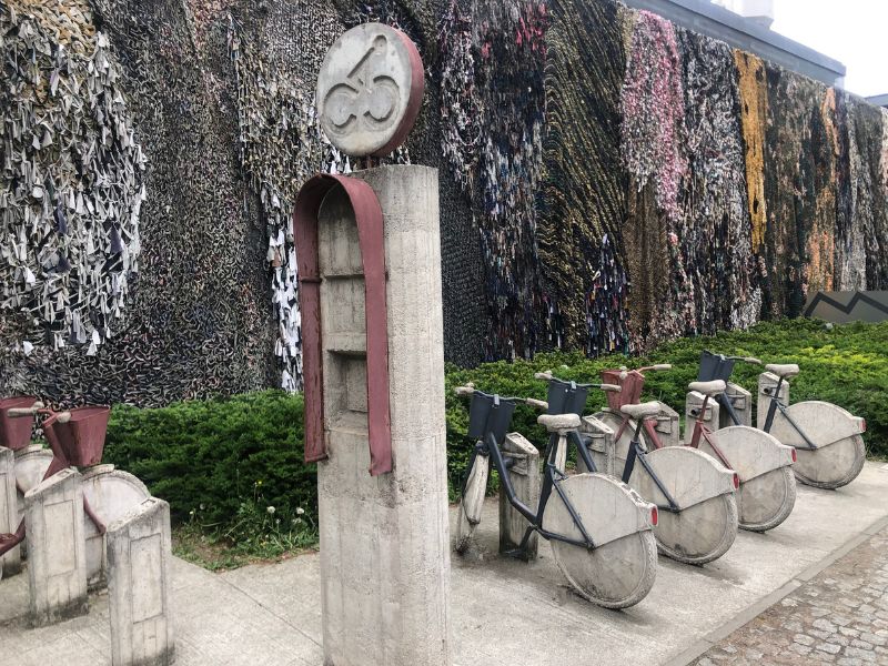 4 Right beside Schindler's factory is the Museum of Contemporary Art, with this outside exhibit of a cement bike transit centre with symbolism that went over my head. But behind it is a wall mural made of old clothing that Ukranian women and children mesh into netting to camouflage their churches and community buildings to prevent bombing by Russia. "Laughing is Suspicious."