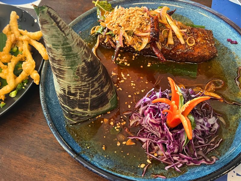 Grilled salmon steak, served with rice wrapped in banana leaf